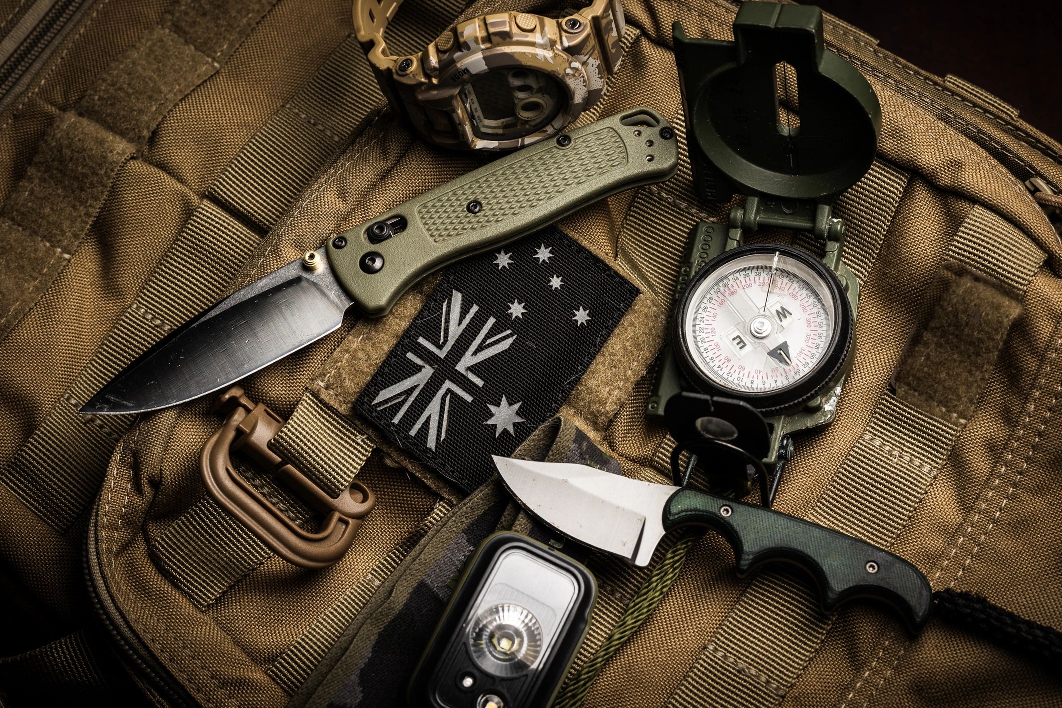 Flat lay of tactical everyday carry gear on a backpack