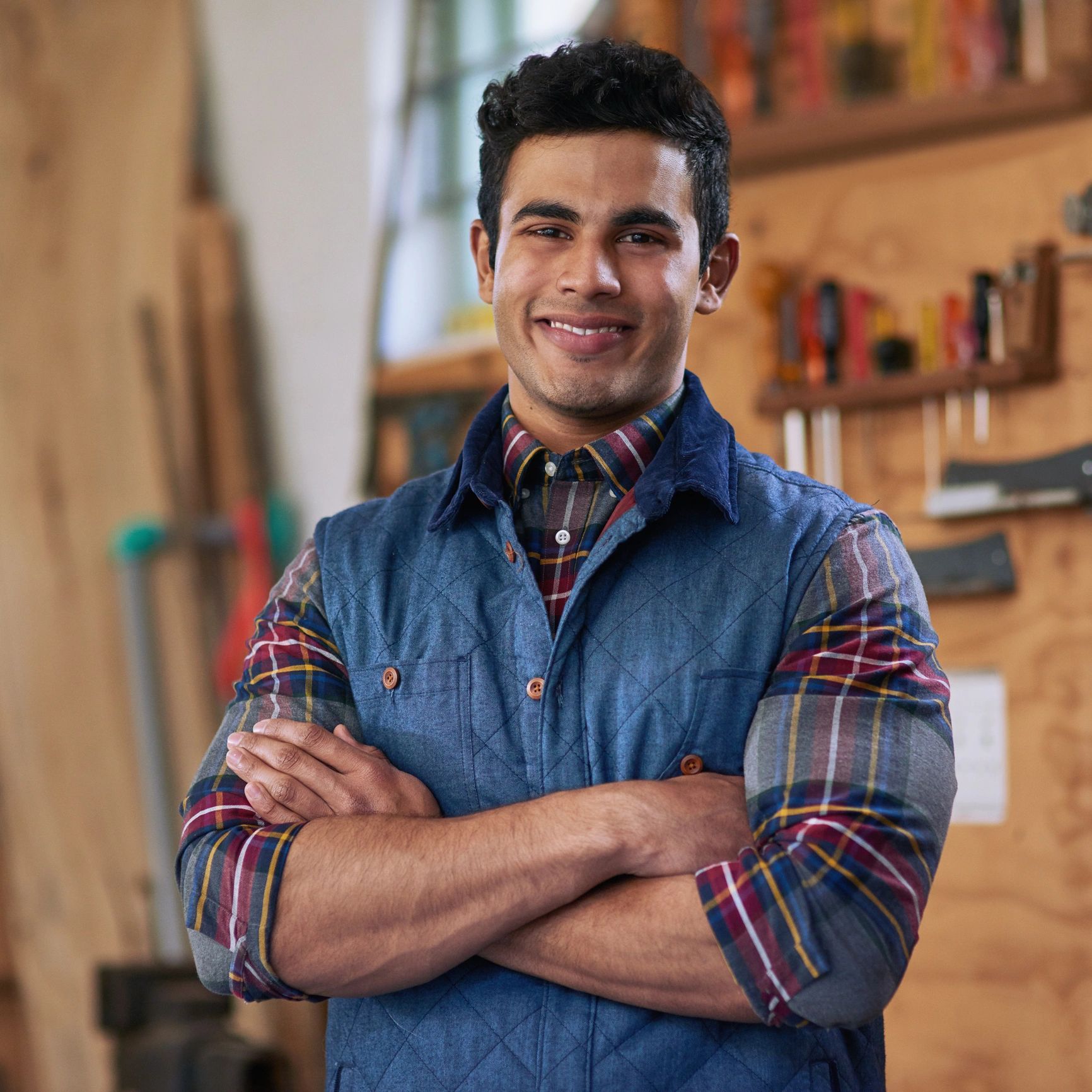 Person standing in a workshop with arms folded