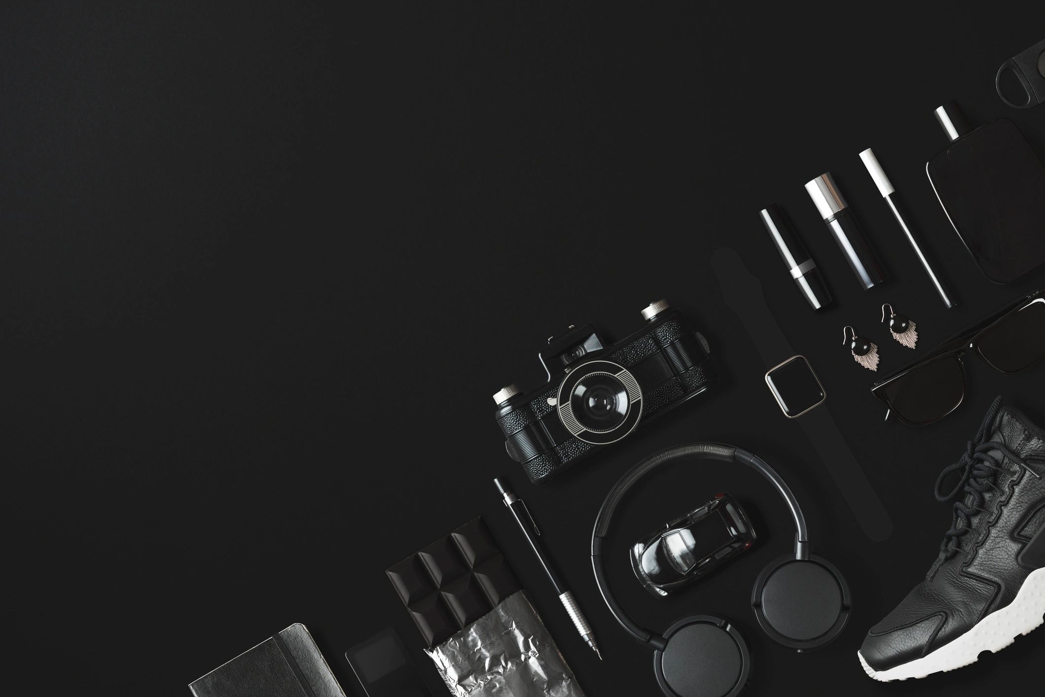 Black everyday carry items flat lay on a dark background